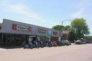 A close-up of Petersen Honda's storefront with motorcycles lined up along the sidewalk.